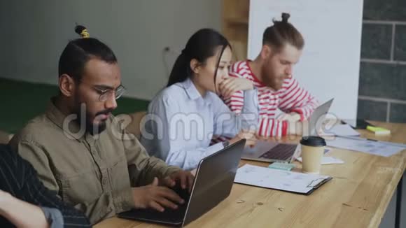 从事技术启动项目的多族裔同事团队非裔美国人集中在手提电脑上打字视频的预览图