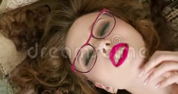 戴眼镜的女人在沙发上躺着的时候试图勾引你特写肖像视频的预览图