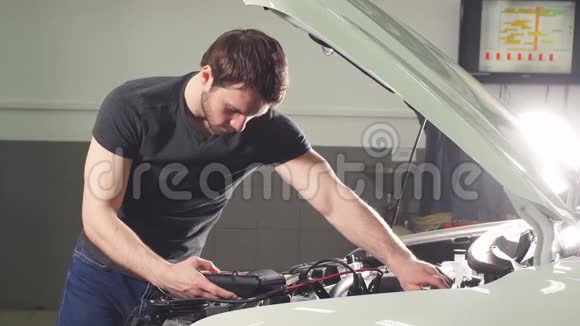 汽车机械师站在汽车附近的一家汽车修理店里开着头罩和做笔记视频的预览图