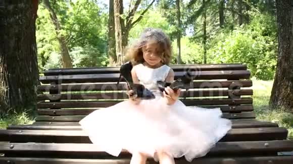 坐在长凳上的小女孩拿着大鞋子视频的预览图
