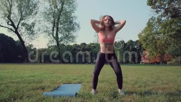年轻的健身女子在大自然中做蹲操视频的预览图