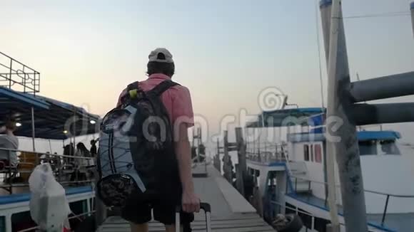 年轻男子背着背包和手提箱沿着码头行走暑假去海边旅行视频的预览图