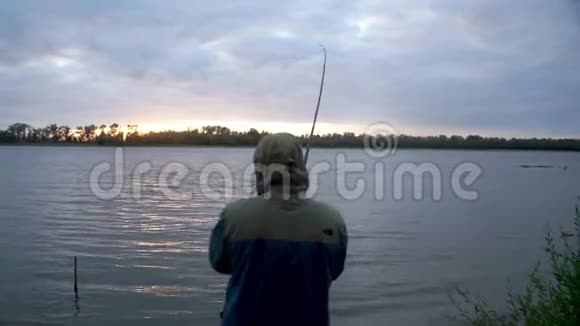 剪影渔夫在咬鱼的过程中钓鱼并旋转鱼卷视频的预览图