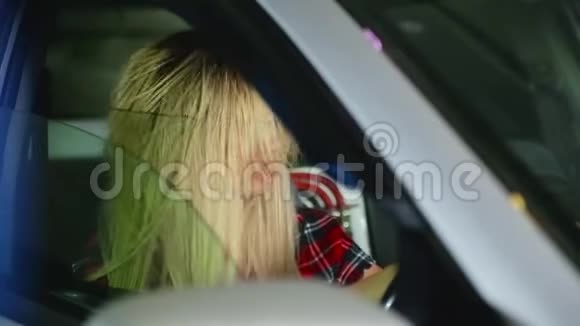 金发碧眼的女孩坐在车里大声听着音乐从这样体积的女孩的头发像被风吹过一样膨胀视频的预览图