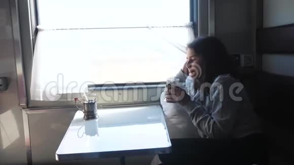 铁路旅行概念看着窗外的小女孩在车厢里喝茶穿深色衣服的女孩喝酒视频的预览图