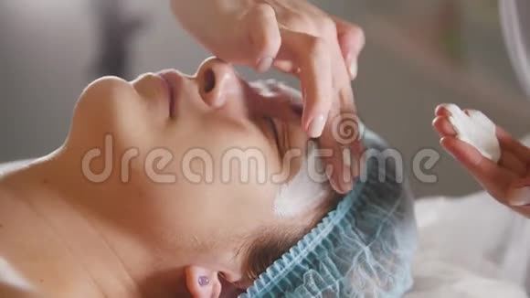 一个美容师在一家美容院一个女人的面部特写戴上面具视频的预览图
