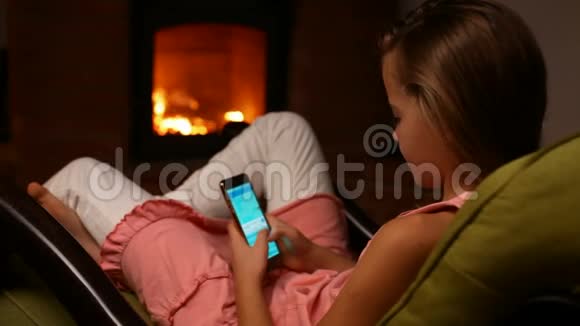 年轻女孩坐在摇椅上用智能手机视频的预览图