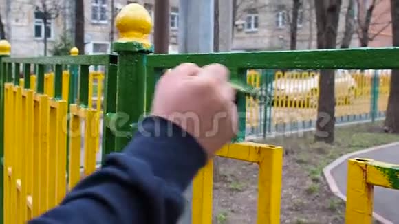 工人用绿色油漆刷一道黄色和绿色的金属栅栏视频的预览图
