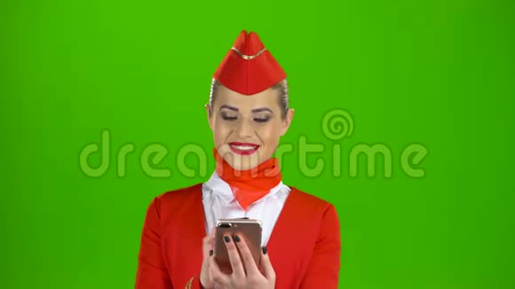 穿红色衣服的女孩看着手机正在翻阅照片绿色屏幕视频的预览图