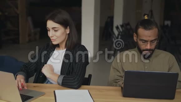 两位年轻的女性和男性自由职业者使用笔记本电脑在同事办公室工作视频的预览图