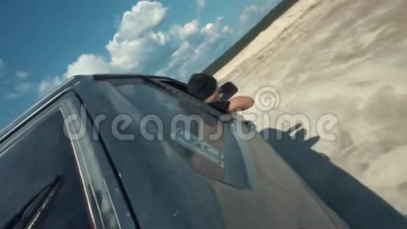 从黑色俄罗斯汽车侧面的近景在沙质表面上移动人从车外看蓝色视频的预览图