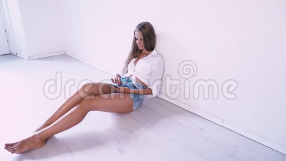 美丽的女孩坐在一个白色的房间里在打电话视频的预览图