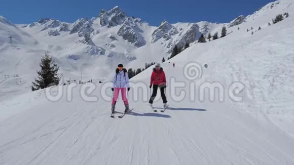 两名女子滑雪者滑下冬季山的理想斜坡视频的预览图