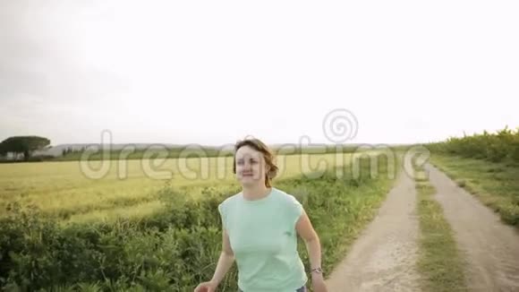 年轻的白种人女孩享受生活在西班牙农村的道路上慢跑穿过农村的麦田视频的预览图