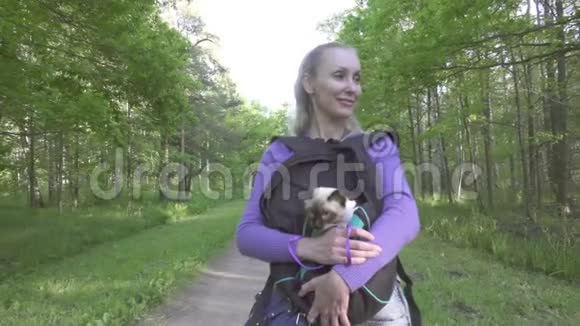那个年轻的女人背着一只猫在公园里散步视频的预览图