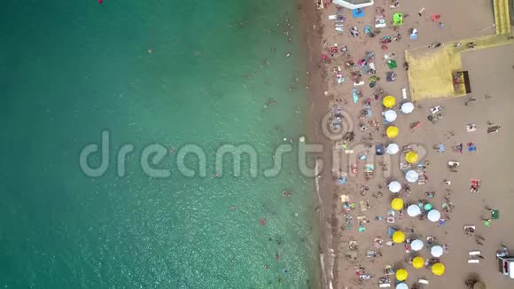 空中海滩的俯视图人们在海中洗澡在岸上打着木制的沙滩伞视频的预览图