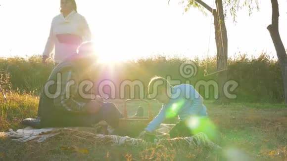 家庭野餐老人带着孙子孙女坐在毯子上的篮子旁手里拿着水果在春天休闲视频的预览图