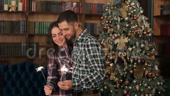 幸福的一对夫妇在圣诞树旁拿着火花视频的预览图