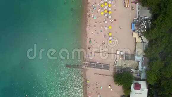 空中海滩的俯视图人们在海中洗澡在岸上打着木制的沙滩伞视频的预览图