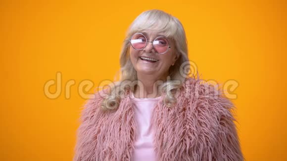 有趣的积极老年女性穿着粉红色外套做摇臂手势玩得开心视频的预览图