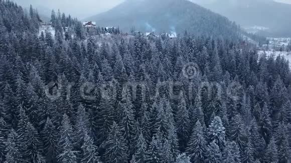 在冬季揭示山区有人居住地区的空中雪山山坡上的山村建筑视频的预览图