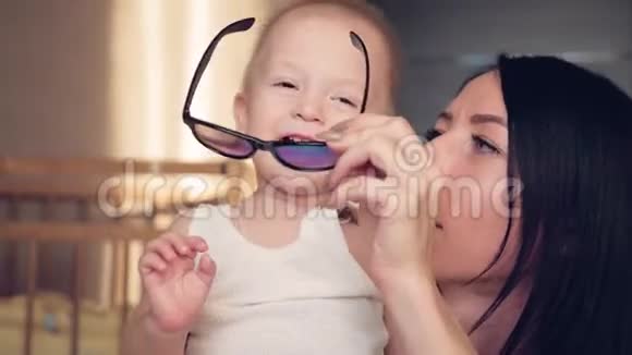 妈妈和小儿子试着戴上有趣的眼镜玩得很开心幸福的家庭在家玩视频的预览图
