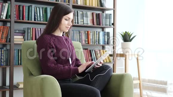 桌上电脑上的休闲坐着的女人听音乐视频的预览图