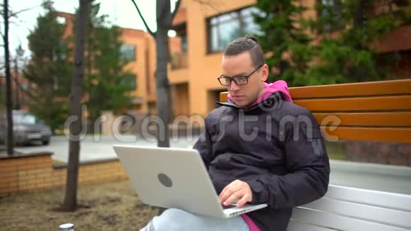 在笔记本电脑上工作的人微笑着在户外多利射击西班牙裔男子戴眼镜工作与笔记本电脑一幅肖像画视频的预览图