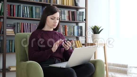 女士在办公室里坐在沙发上浏览智能手机视频的预览图