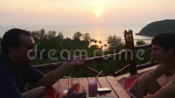 两个商人坐在山上的咖啡馆里俯瞰大海和令人惊叹的日落3840x2160视频的预览图