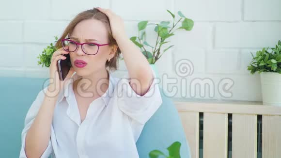 愤怒的女人在家里坐在沙发上用手机说话视频的预览图