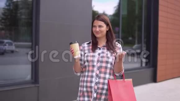 一个漂亮的女孩带着包裹去购物手里拿着一杯咖啡慢动作高清高清视频的预览图