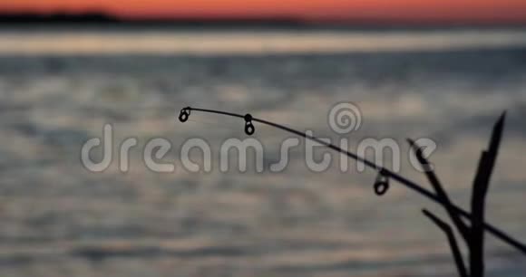 日落时在湖边钓鱼捕鱼背景日落时的钓鱼竿视频的预览图