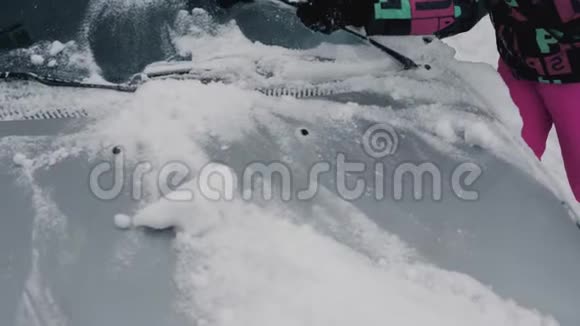 女人用刷子积极清理你的车从冬天的雪视频的预览图