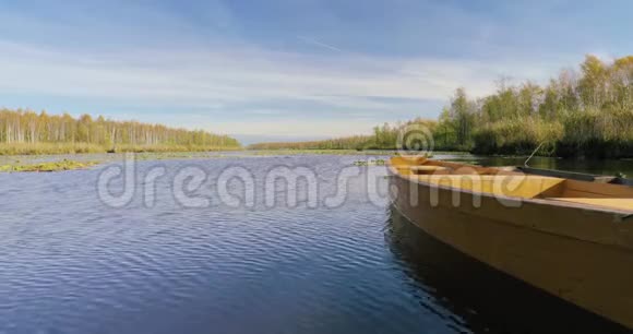 在美丽的秋日晴天停泊在湖边或河边的老式木制划艇视频的预览图