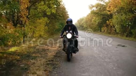 在阳光明媚的秋天身穿黑色头盔和皮夹克的面目全非的男子在路边停下了老式摩托车视频的预览图