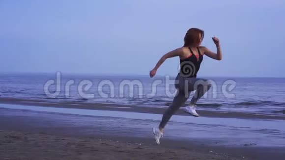 一个夏天的早晨穿着运动制服的红发苗条的中年妇女沿着沙滩奔跑视频的预览图