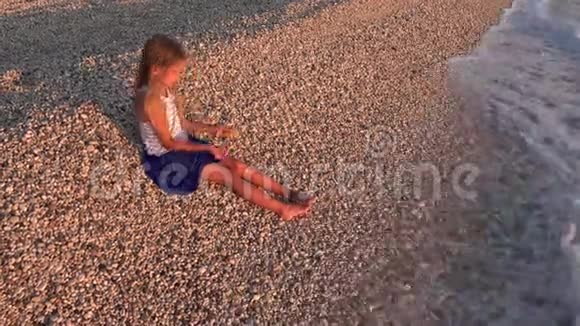 在夕阳下的沙滩上玩耍的孩子微笑的女孩在海水中扔球视频的预览图