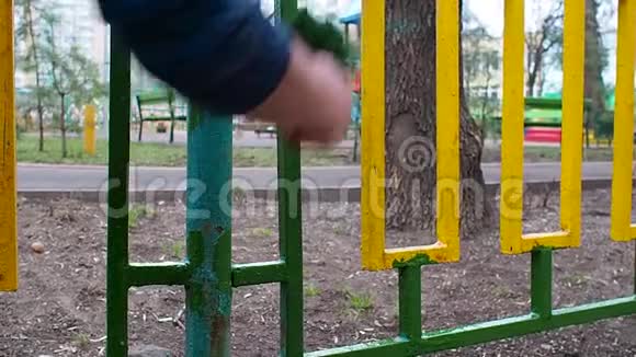 一名工人在后台操场上画一道黄绿色的篱笆上面画着绿色的滚筒视频的预览图