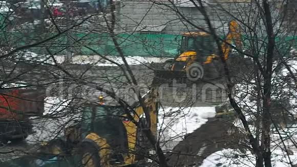 小型挖掘机在冬季在雪下挖掘建筑工地的土壤视频的预览图