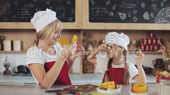 马瑟和女儿在厨房玩得开心他们准备蔬菜沙拉家庭日烹饪妈妈和女儿的概念视频的预览图
