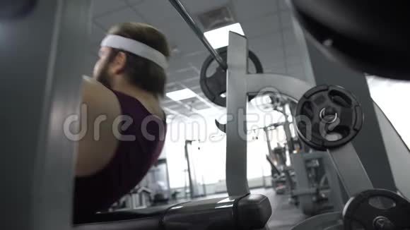 有目的的胖子举起运动杠铃躺在长凳上身体锻炼计划视频的预览图