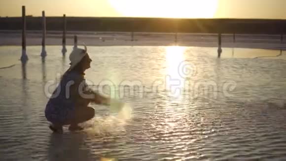 快乐的微笑女孩享受阳光在夕阳的余晖中洒下湖水视频的预览图