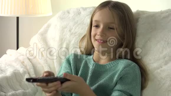 儿童肖像电视带遥控器的女孩在沙发上放松4K教练视频的预览图