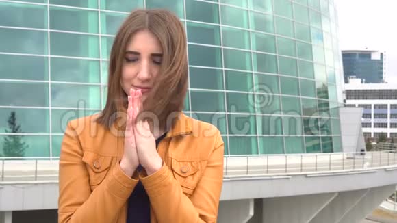 真实人物的肖像非常美丽的女孩在城市的室外镜头祈祷视频的预览图