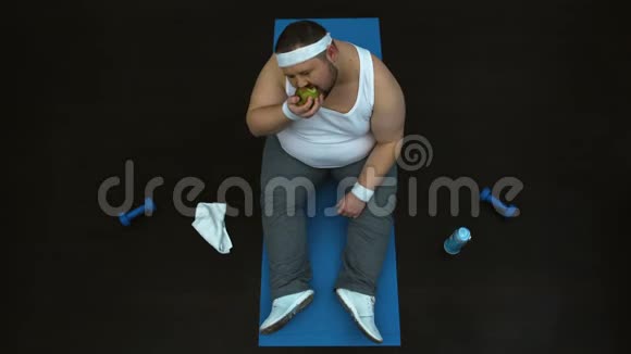 饥饿的胖子健身后吃绿苹果健康营养俯视图视频的预览图