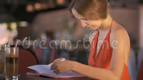 女生阅读日记坐在饮料旁的桌子上视频的预览图