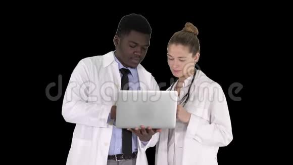 医务人员站在阿尔法频道的灰色笔记本电脑前工作视频的预览图