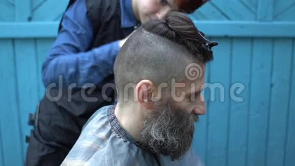 女理发师在户外美发沙龙剪发电动剃须刀和梳子的中年男子胡须视频的预览图