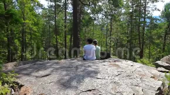 两个女人在岩石悬崖上放松欣赏风景视频的预览图